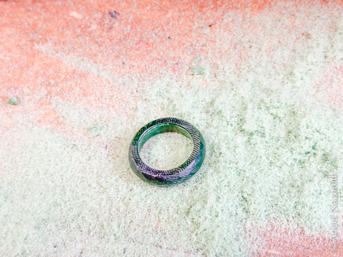 A ring sculpted in wax in the middle of a pile of wax shavings. The ring has lots of deep file marks on it
